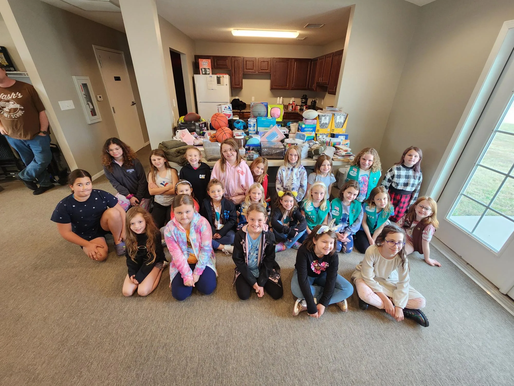 Girl Scouts sit in front of their donation during 2024 Festival of Giving for EmberHope foster kids