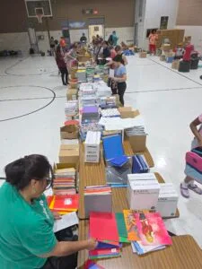 Volunteers packing school supplies in an assembly line