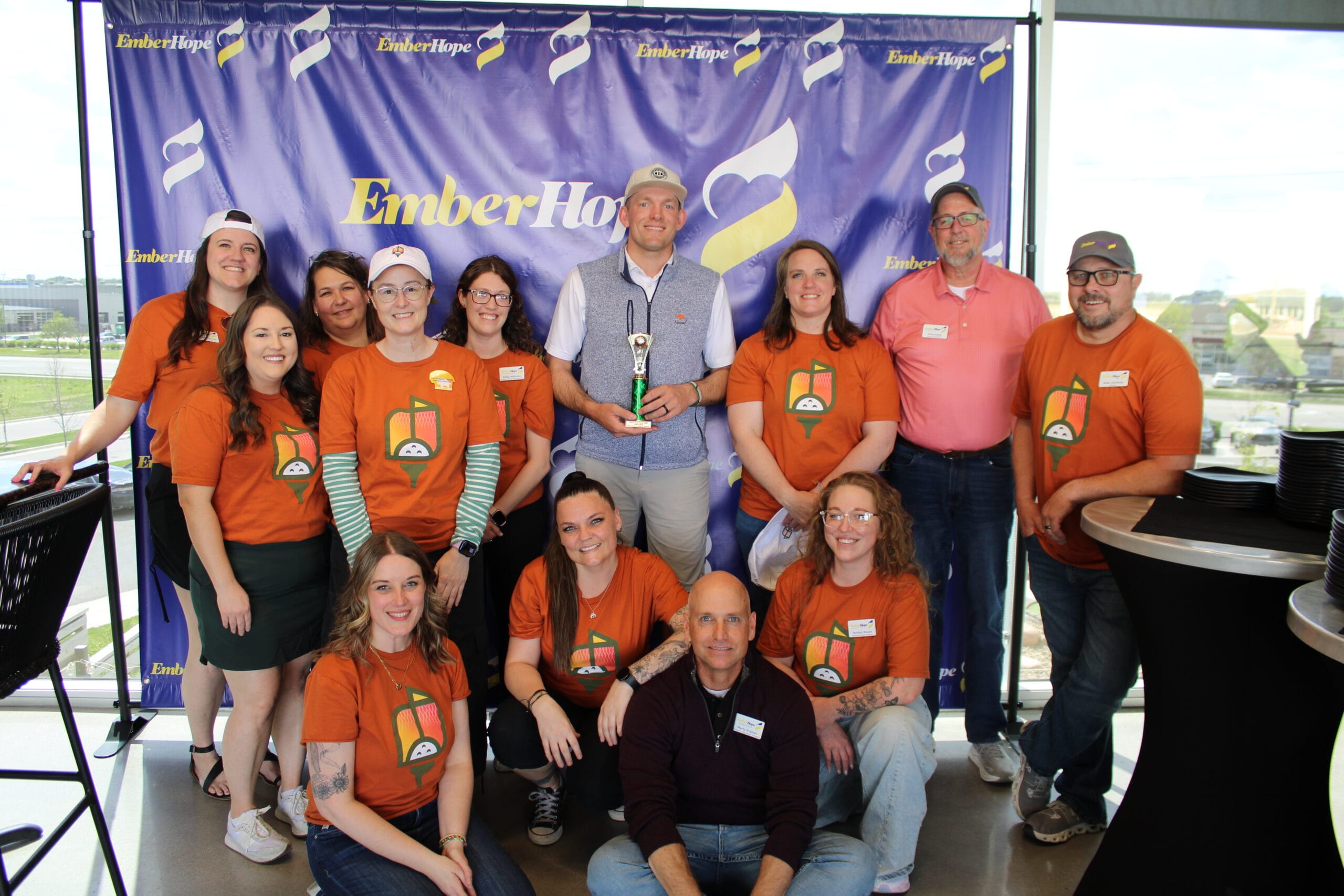 Former Wichita State basketball player Ron Baker takes a photo with his trophy alongside the teams from EmberHope, Gathered, and CASA