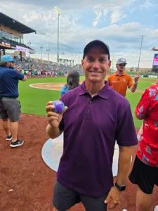 EmberHope Foundation President Marty Kramer holding up the ball for the first pitch